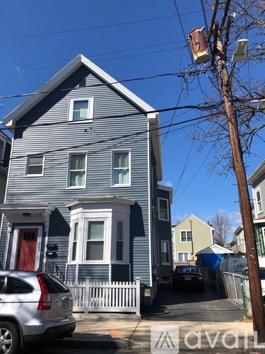 A blue house with a white picket fence and a car parked in front.