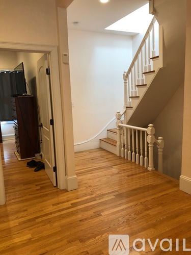 A hallway with a staircase and a TV in the corner.