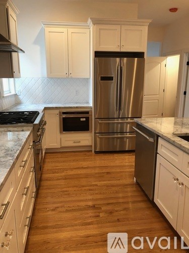 A kitchen with a stainless steel refrigerator and wooden floors.