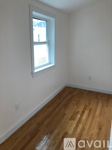 A room with a window and wooden flooring.