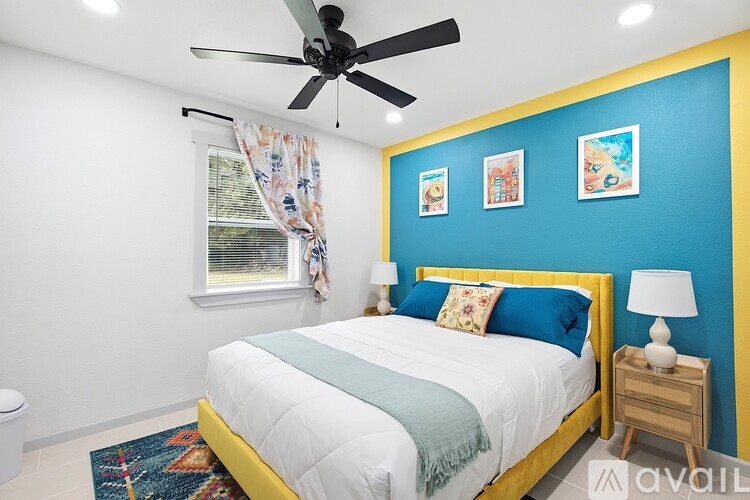 A bedroom with a bed, a ceiling fan, and a window with curtains.