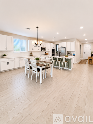 A modern kitchen with white cabinets and a dining table.
