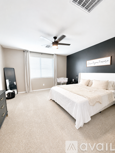 A bedroom with a bed, dresser, and ceiling fan.