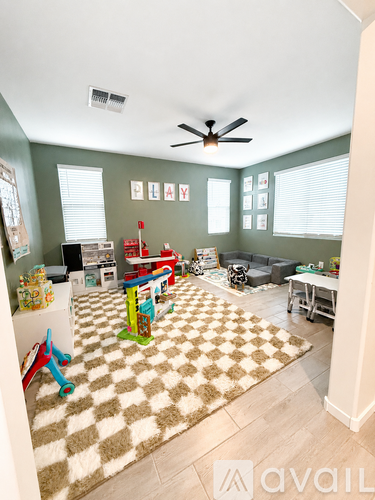 A living room with a rug and a ceiling fan.
