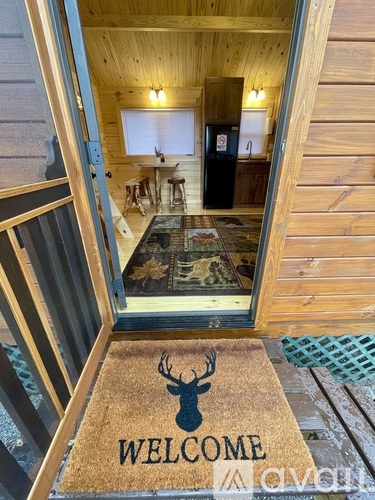 A wooden house entrance with a doormat that says "Welcome".