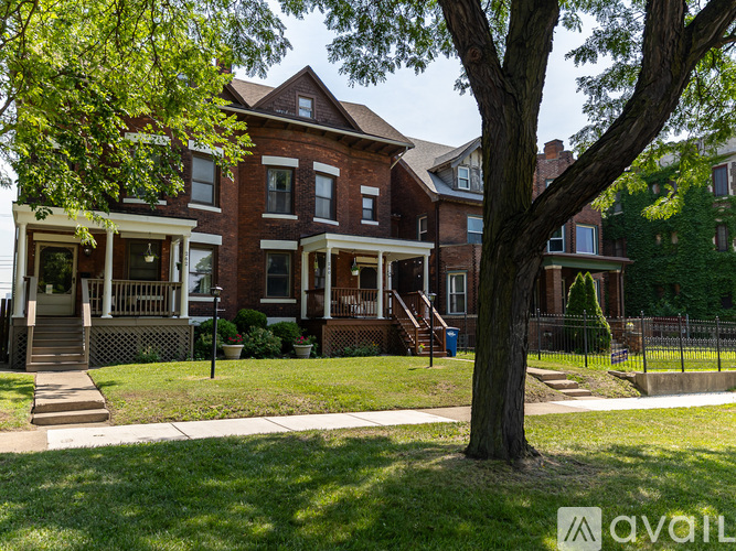 A large red brick house with a tree in front.