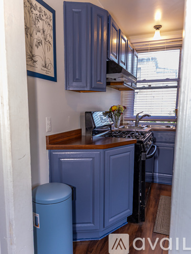 A kitchen with blue cabinets and a blue trash can.