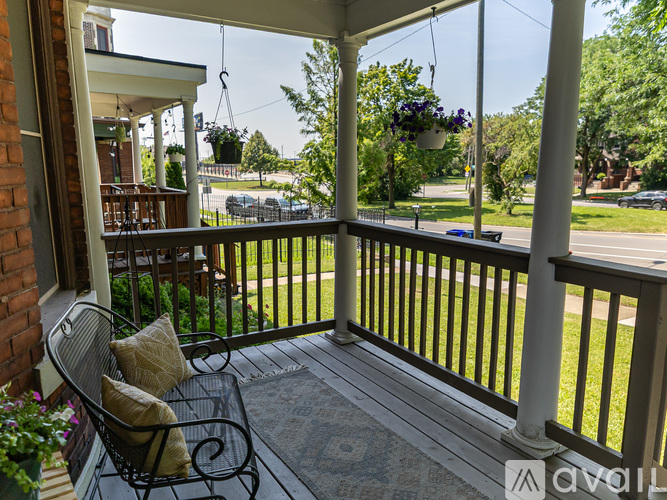 A porch with a bench and a table with a flower pot on it.