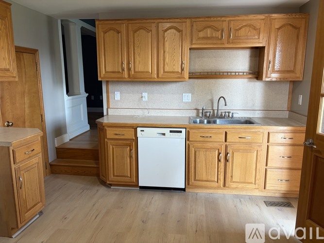 A kitchen with wooden cabinets and a white dishwasher.