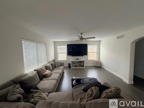 A living room with a grey sofa and a television on a white stand.