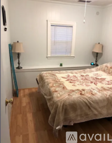 A bedroom with a bed, two lamps, and a window.