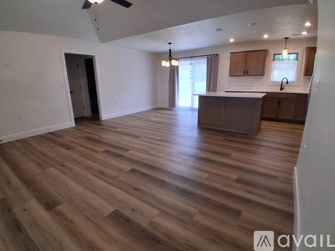 A spacious room with wooden flooring and a ceiling fan.