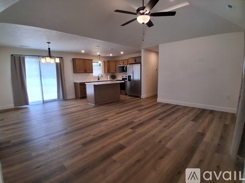 A spacious living room with wooden flooring and a ceiling fan.