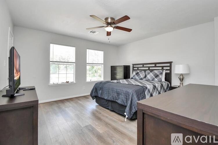 A bedroom with a bed, a television, and a ceiling fan.