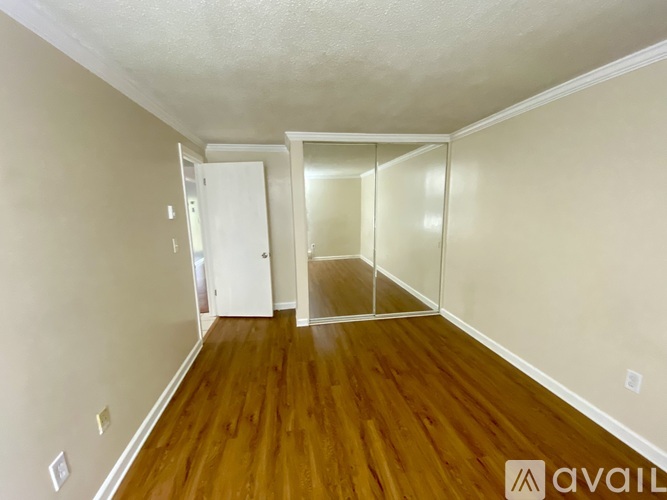 A room with wooden floors and white walls, with a door on the left and a glass door on the right.