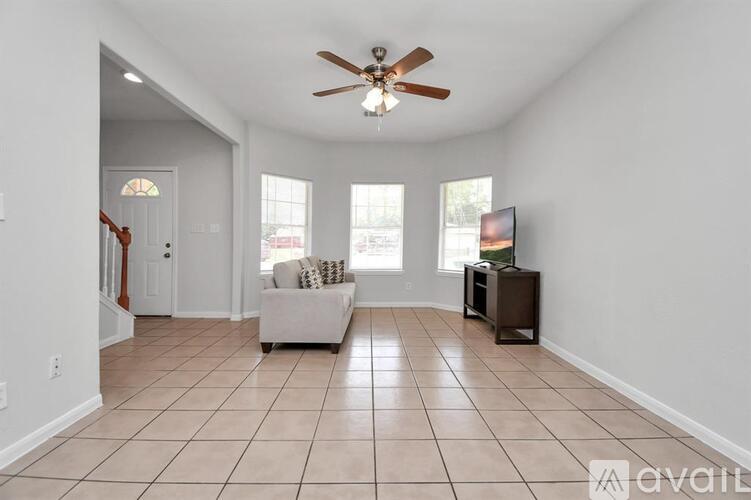 A living room with a couch, a television, and a ceiling fan.