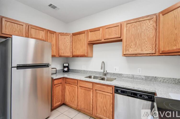 A kitchen with wooden cabinets and a stainless steel refrigerator.