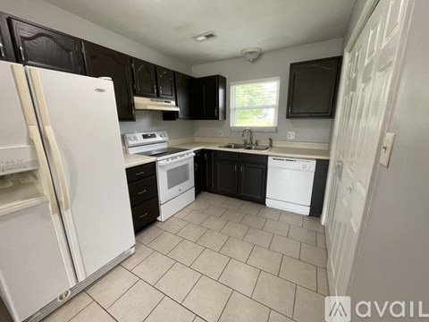 A kitchen with black cabinets and white appliances.