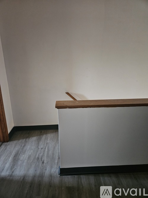 A white reception desk with a wooden top sits in a room with a grey floor.