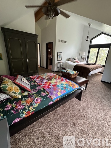 A bedroom with a large bed and a ceiling fan.