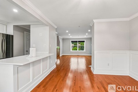 A spacious kitchen with white cabinets and a wooden floor.