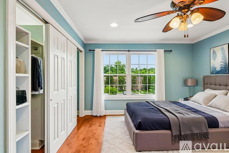A bedroom with a bed, a ceiling fan, and a wardrobe.