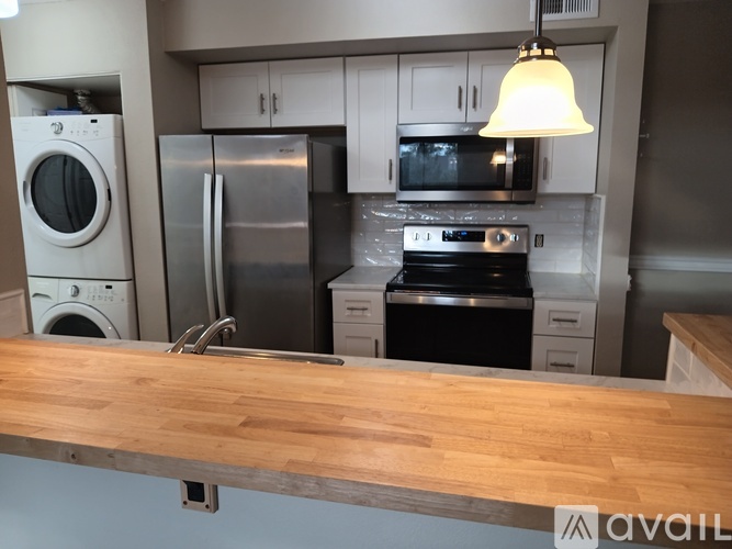 A kitchen with a wooden counter top and stainless steel appliances.