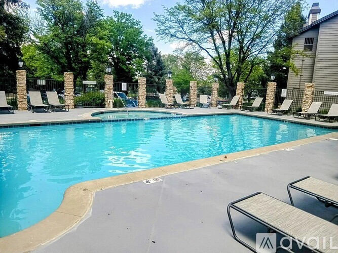 A pool surrounded by lounge chairs and trees.