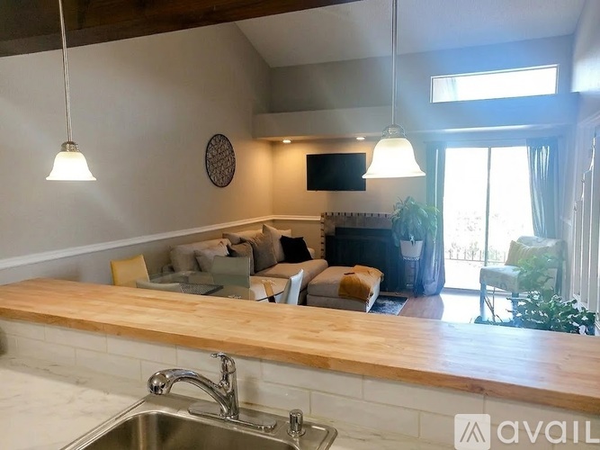 A kitchen with a wooden countertop and a stainless steel sink.