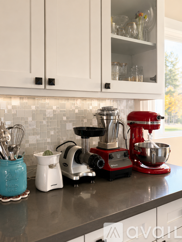 A kitchen counter with a red mixer and a blue container with utensils.