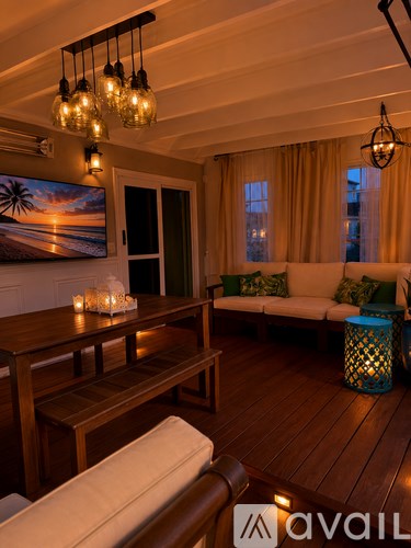 A living room with a wooden floor and a painting of a beach scene on the wall.