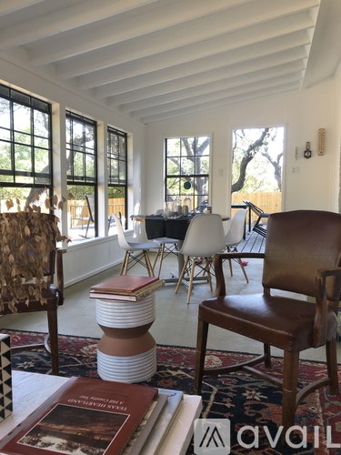 A living room with a brown leather chair and a white chair with a stack of books in front of them.