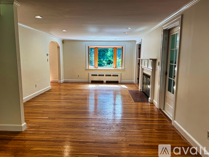 A spacious room with wooden floors and a large window.