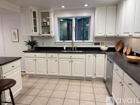 A kitchen with white cabinets and a black countertop.