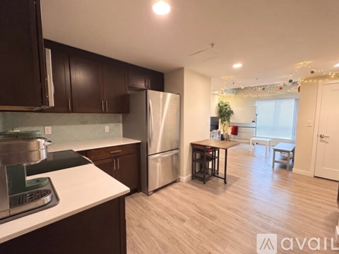 A kitchen with dark brown cabinets and a stainless steel refrigerator.
