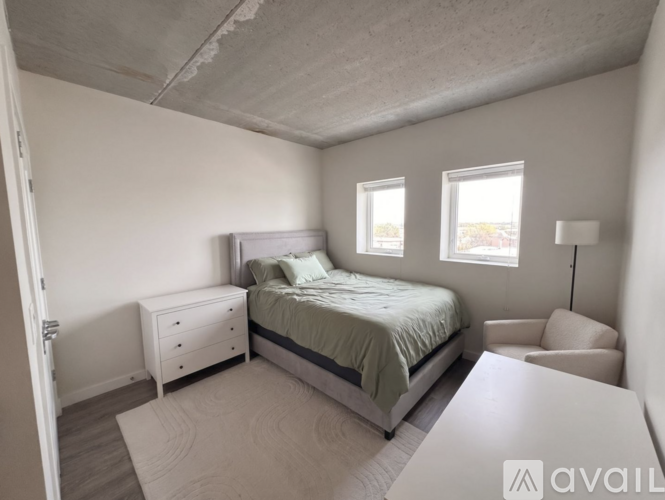 A bedroom with a bed, nightstand, and chair.