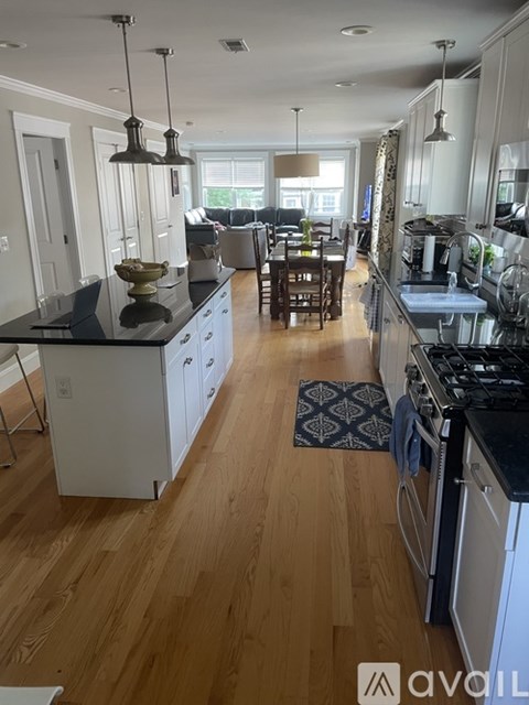 A kitchen with wooden floors and black countertops.