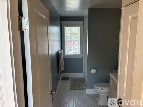 A bathroom with a toilet, sink, and window.