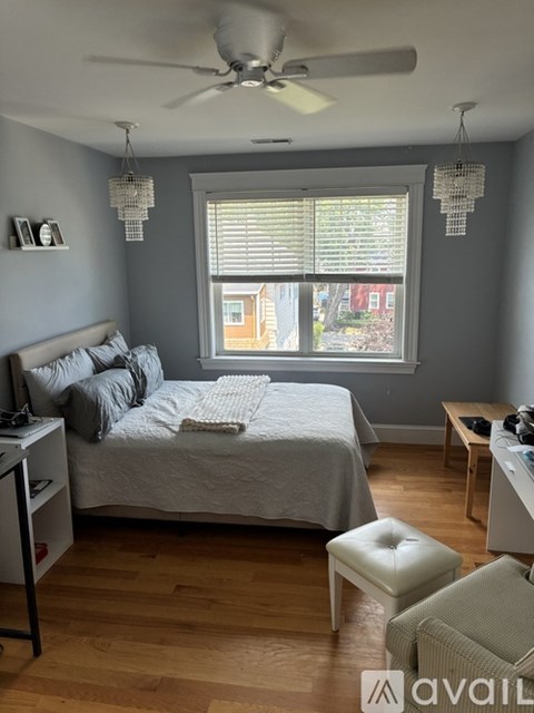 A bedroom with a bed, a chair, and a window with blinds.