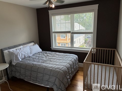 A bedroom with a bed, a fan, and a crib.