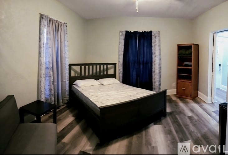 A bedroom with a large bed and a wooden cabinet.