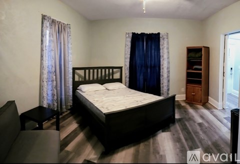 A bedroom with a large bed and a wooden cabinet.