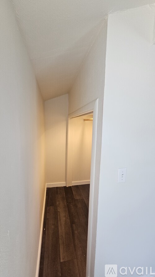 A hallway with a wooden floor and white walls.
