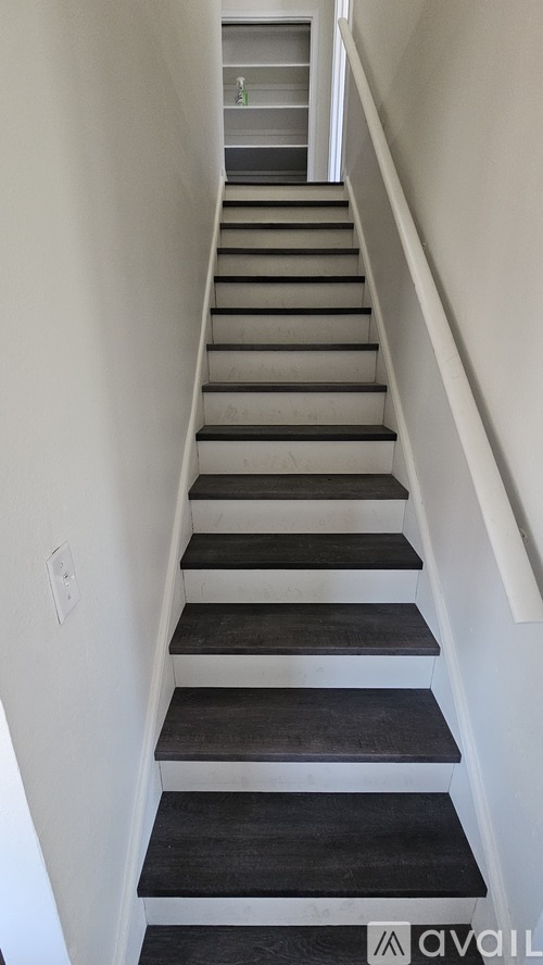 A staircase with a white wall on the left and a white railing on the right.