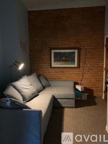 A living room with a couch and a painting on the wall.