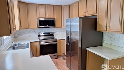 A kitchen with wooden cabinets and a black refrigerator.