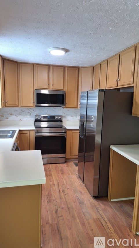 A kitchen with wooden cabinets and a black refrigerator.