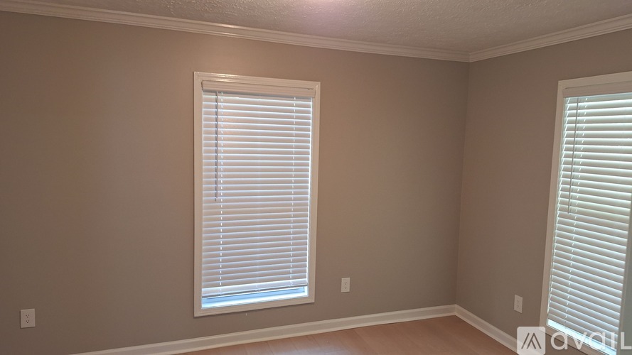 A room with a window covered in white blinds.