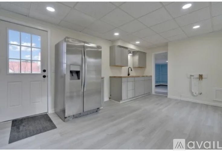 A kitchen with a refrigerator, sink, and cabinets.