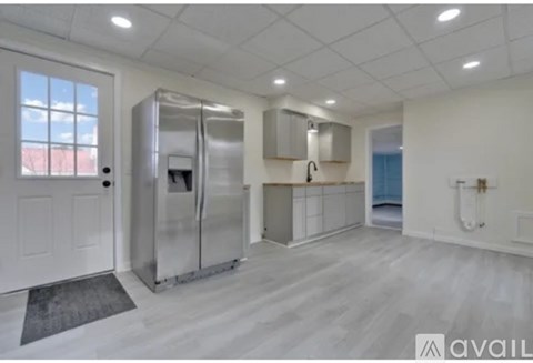 A kitchen with a refrigerator, sink, and cabinets.